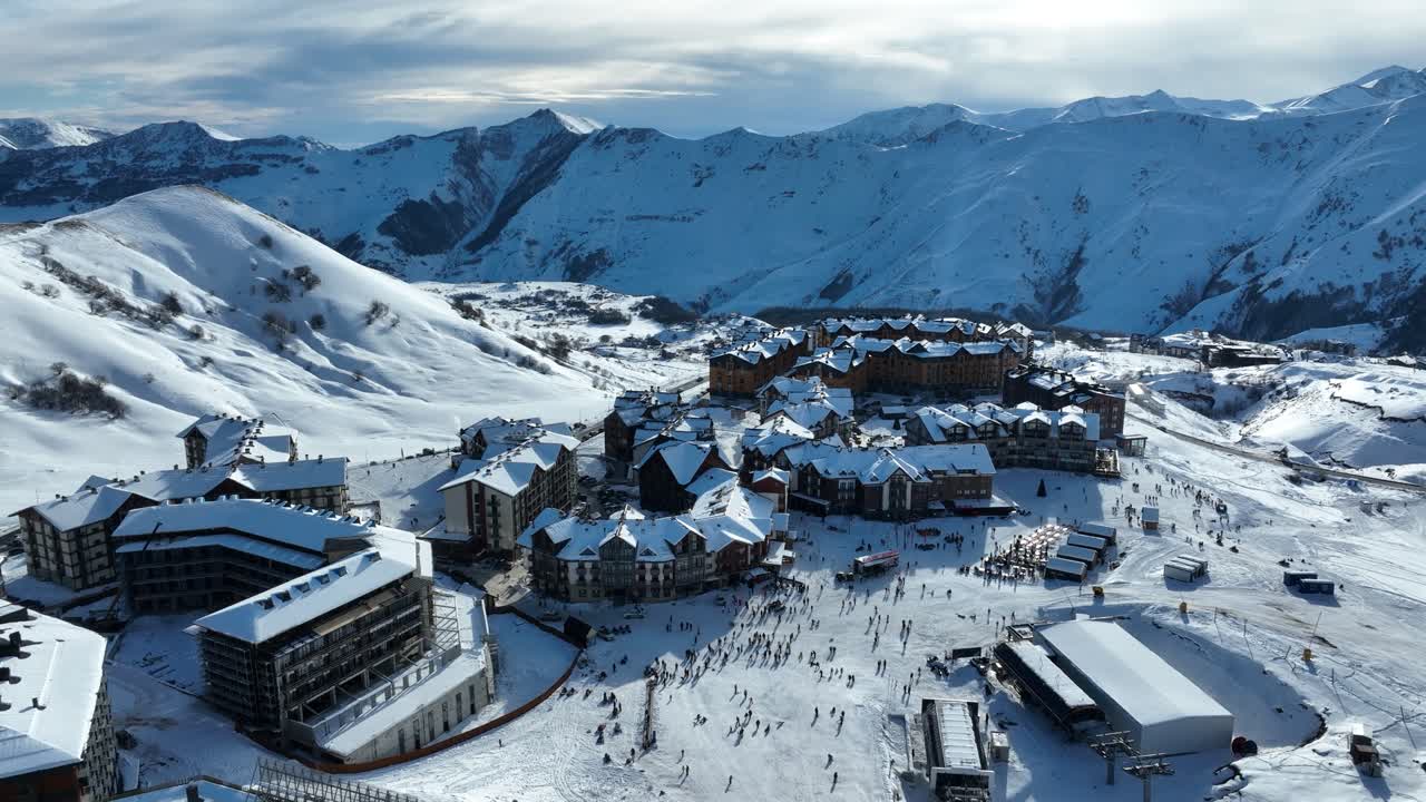 A vibrant ski resort nestled in snow-covered mountains, bustling with skiers and visitors preparing for a day on the slopes under a clear sky