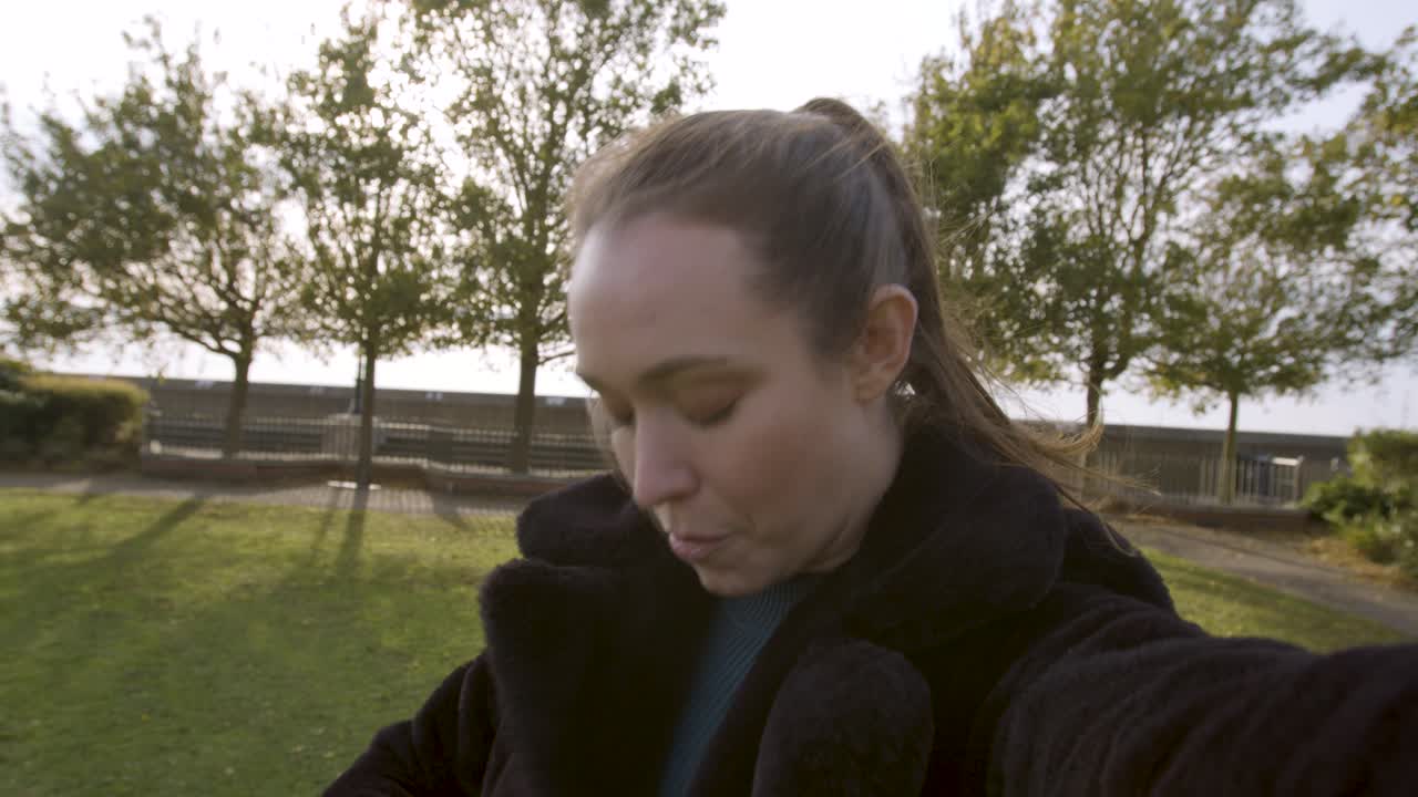 женщина, общающаяся со своими подписчиками в парке, перемещает камеру, показывая окружающую обстановку