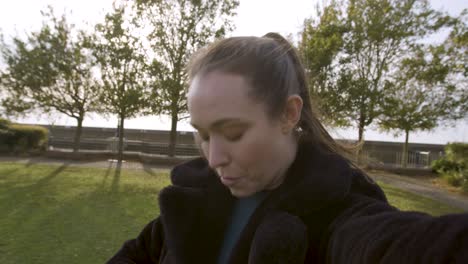 influencer femenina hablando con sus seguidores en un parque moviendo la cámara mostrando su entorno