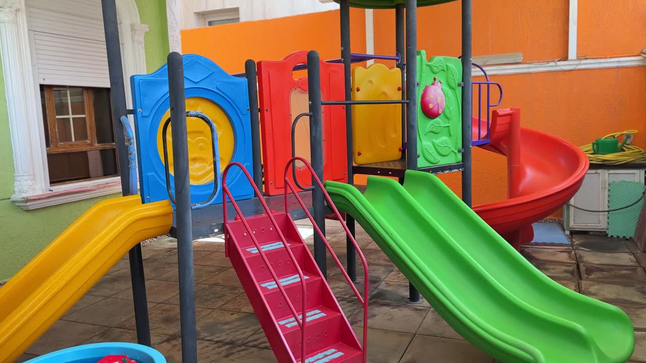 Bright 4K video of a cheerful playground with colorful slides and structures. Perfect for education, childhood, daycare, family, or outdoor recreation footage.