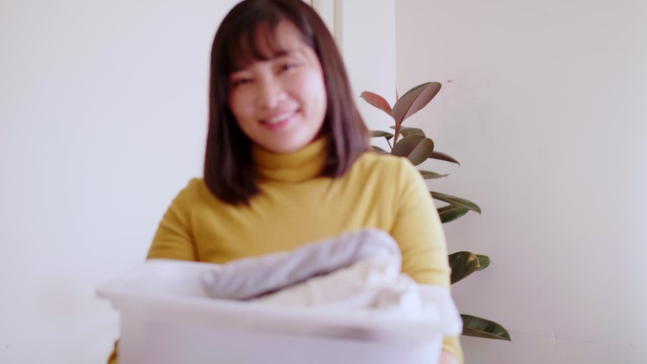 기부 옷 상자를 들고 카메라를 보고 젊은 아시아 여자의 초상화