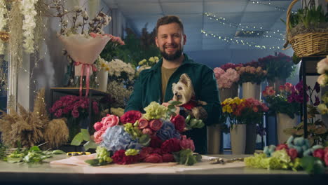 florist keeps dog in hands and looks at camera