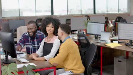 tres felices colegas diversos discutiendo sobre una computadora en la oficina