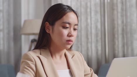 아픈 아시아 사업가 여성이 집에서 거실에서 노트북으로 일하는 동안 차가운