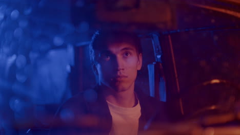 man sitting in car at night, adjusting and looking in rear view mirror