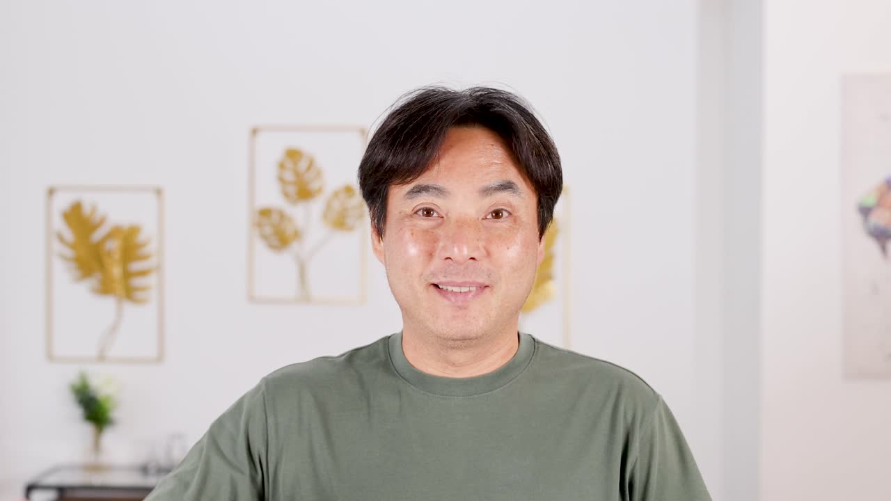 A man in a green shirt shows a thumbs down gesture, expressing disapproval in a brightly lit room