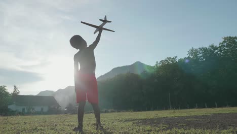 a boy with a toy airplane in the meadow