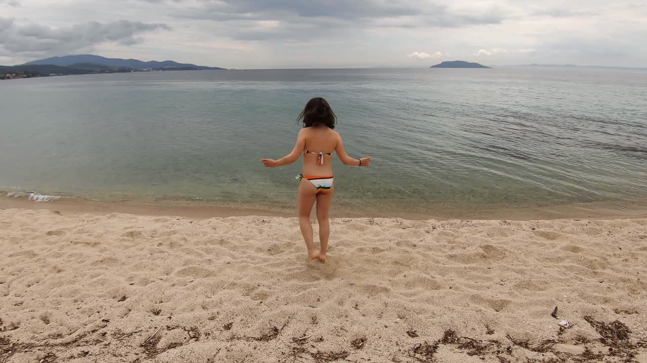 수영복을 입고 모래사장에서 놀고 점프하는 20대 행복한 소녀