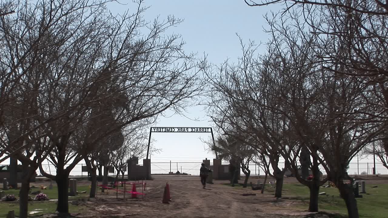 사람들은 묘지 주변을 걷고 차들은 지나간다