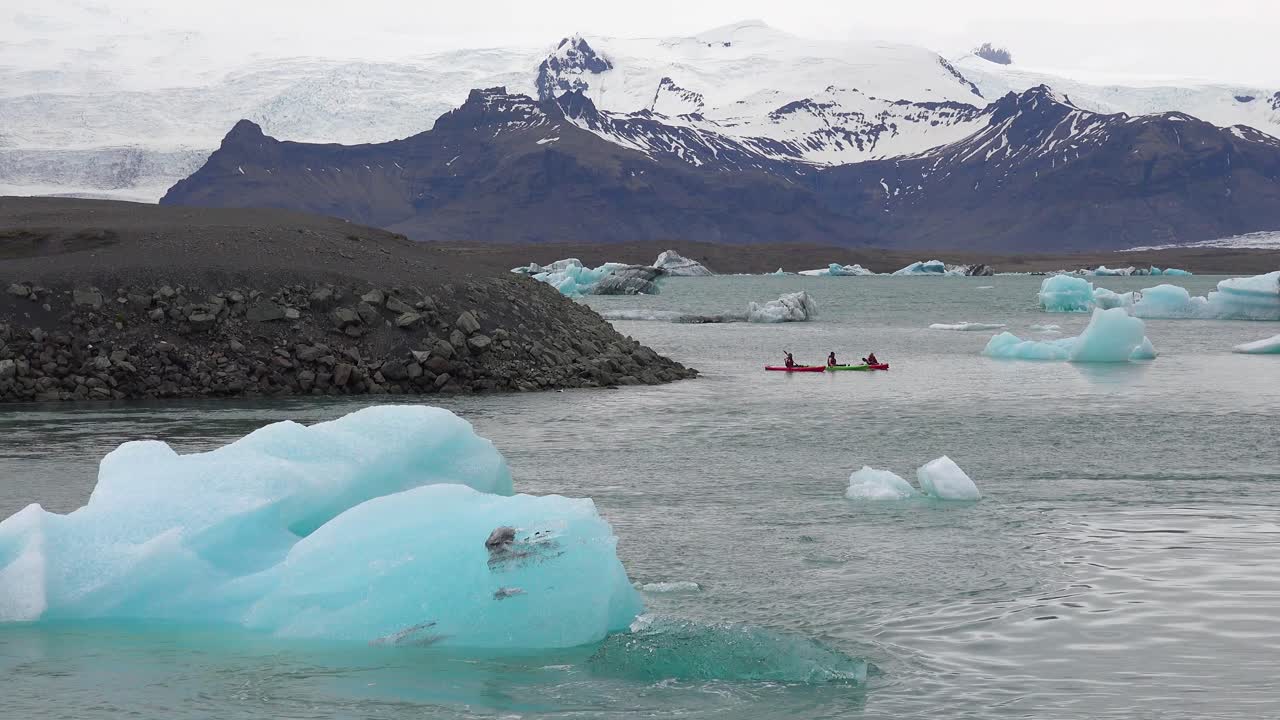 kayakers는 jokulsarlon iceland에서 녹는 빙하 석호를 통과합니다.