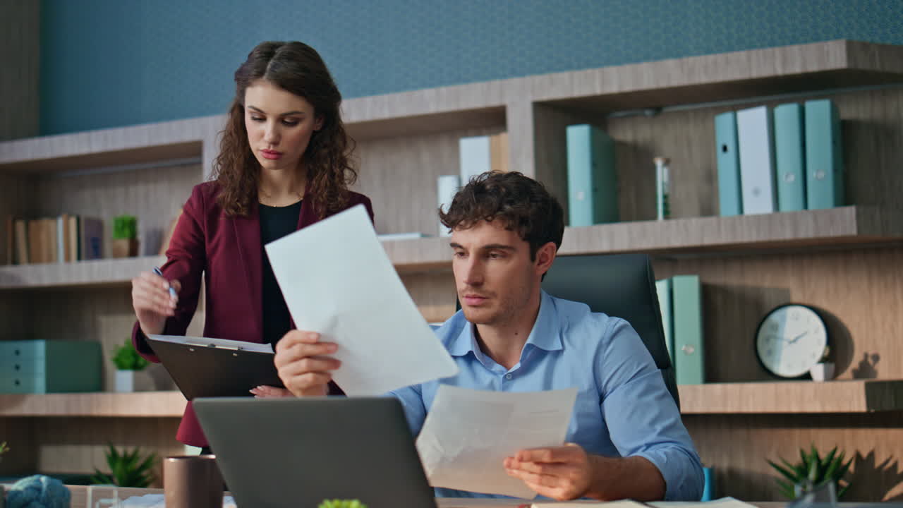 Confident ceo examining documents talking with woman assistant in office closeup