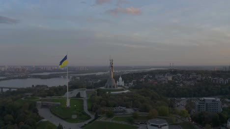 ukrainian flag and the motherland monument on sunrise in kyiv, ukraine