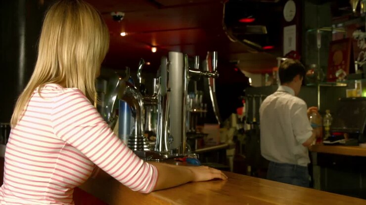 Donna a cui viene servito un drink al bar