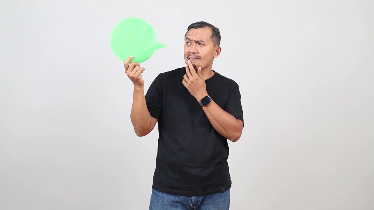 Pria dewasa berpikir sambil memegang kertas gelembung ucapan hijau, memberikan suara, ulasan, komentar, atau pesan di ruang mockup