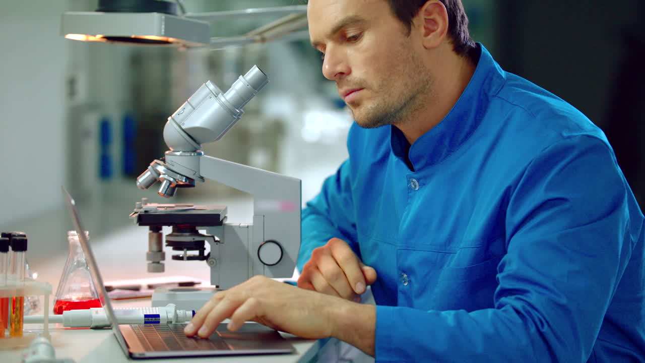 Male scientist looking microscope in lab. Microscope laboratory research