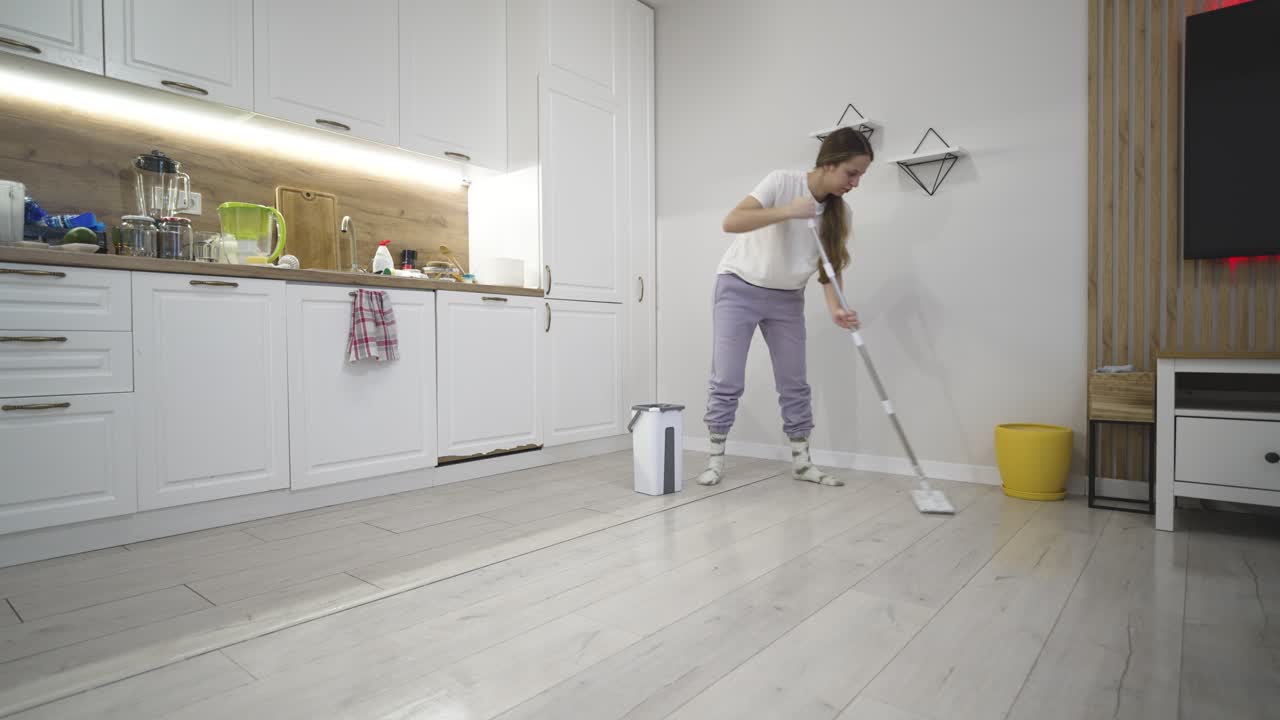 Kvinne vasker gulvet i et hjemmeinteriør, som skildrer husarbeid, renslighet og daglig rutine i hjemmet, med vekt på hygiene, omsorg og organisert livsstil.