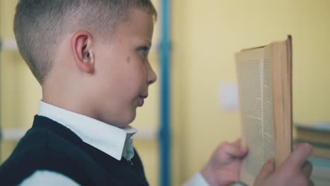 kid turns page of textbook in room on blurred background