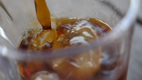 Macro-slow-motion-of-colored-soda-being-poured-into-a-glass-with-ice