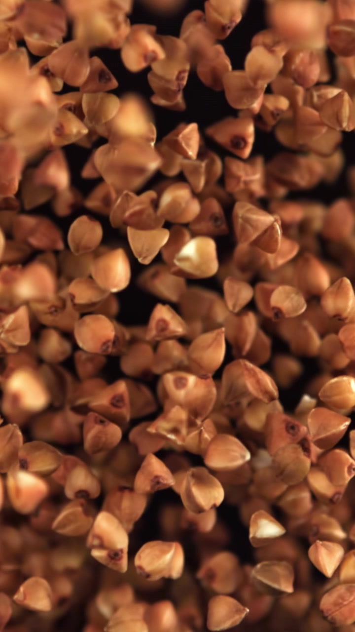 Buckwheat Grains Falling in Slow Motion on Black Background