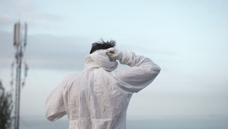 man in protection suit standing on the edge of the roof put off the respirator and fall on his knees