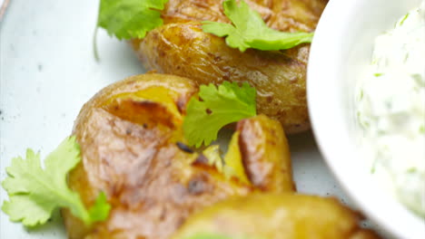 Close-up-of-roasted-potatoes-on-a-white-plate-with-garlic-dip