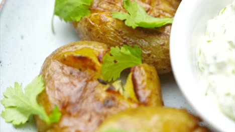 close up of roasted potatoes on a white plate with garlic dip