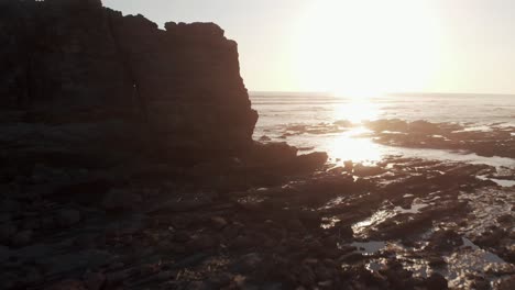 bright sunlight on the rocky coast in costa rica with ocean waves splashing during sunrise - drone shot