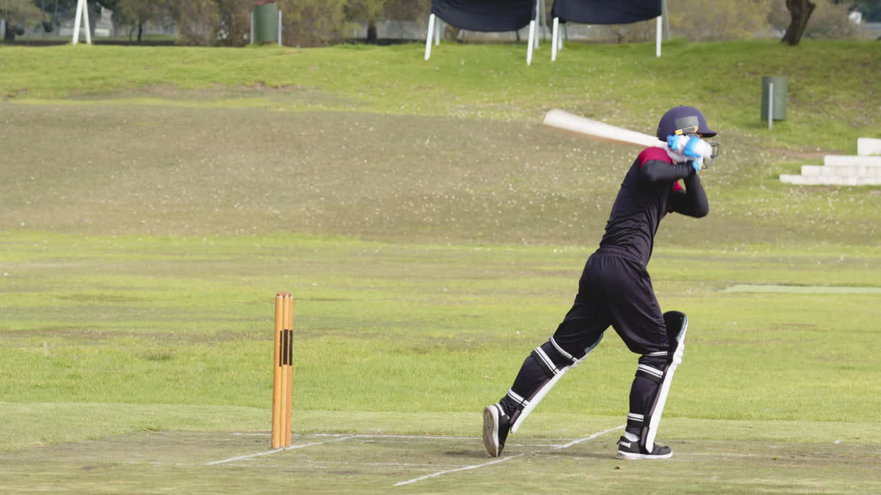 Male cricket players playing cricket, batter preparing to hit the ball with bat on pitch