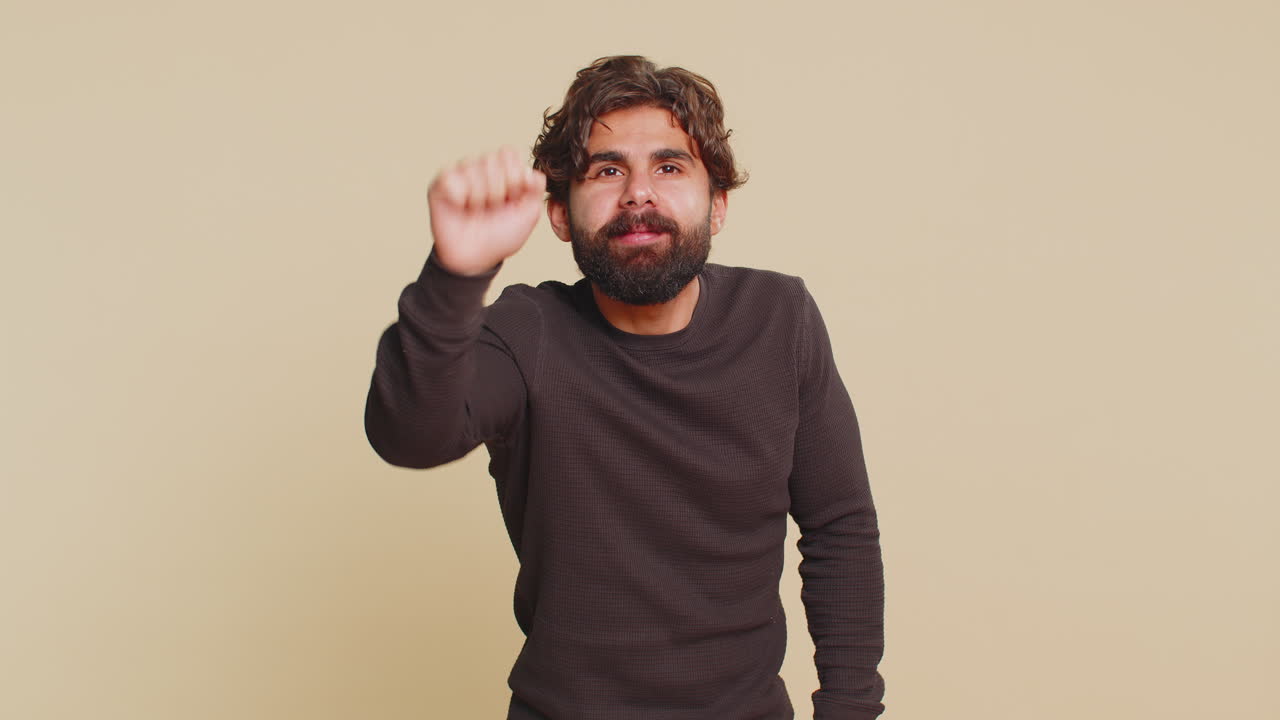 Confused indian hispanic man knocking door gesture asking who is at home against beige background