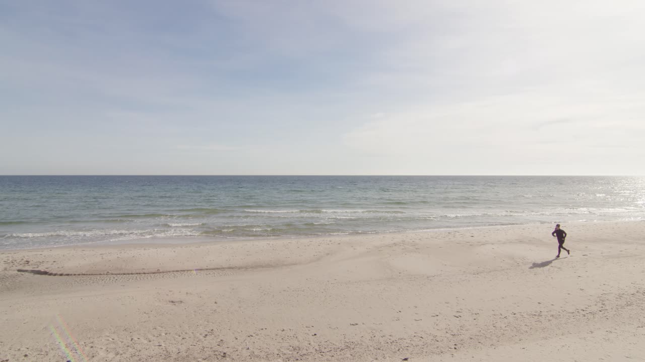 걷는 여자는 bly 하늘 녹색 물 밝은 하얀 모래와 화창한 따뜻한 날에 열대 해변에서 조깅을 시작합니다