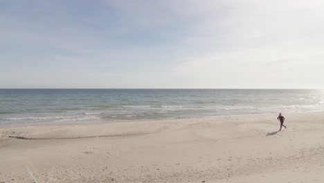 walking woman starts jogging at tropical beach on a sunny warm day with bly sky green water bright white sand