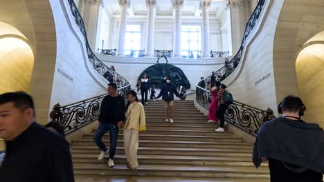 tourists walking up the ornate staircase in museum