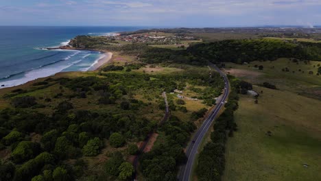 Vehículos-Que-Circulan-Por-La-Carretera-De-La-Costa-Junto-A-Exuberantes-Campos-Verdes---Pueblo-Costero-Con-Vistas-Al-Océano---Lennox-Head,-Nsw,-Australia