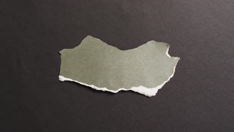 video of close up of torn piece of green paper on black background