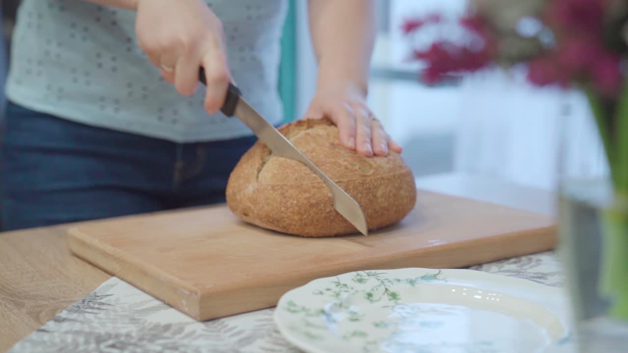 Cutting fresh loaf of bread on the dining room table, establisher