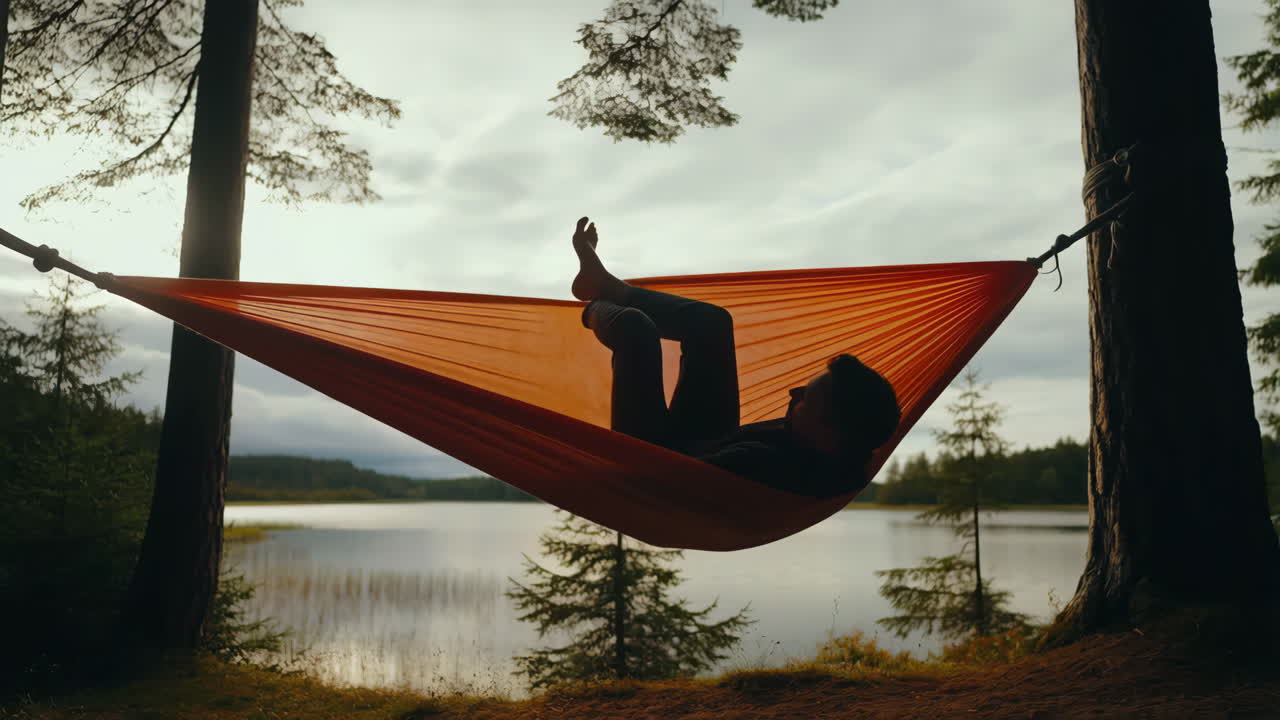 Person Relaxing in a Hammock by a Serene Lake in the Forest