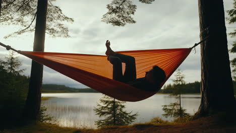 person relaxing in a hammock by a serene lake in the forest