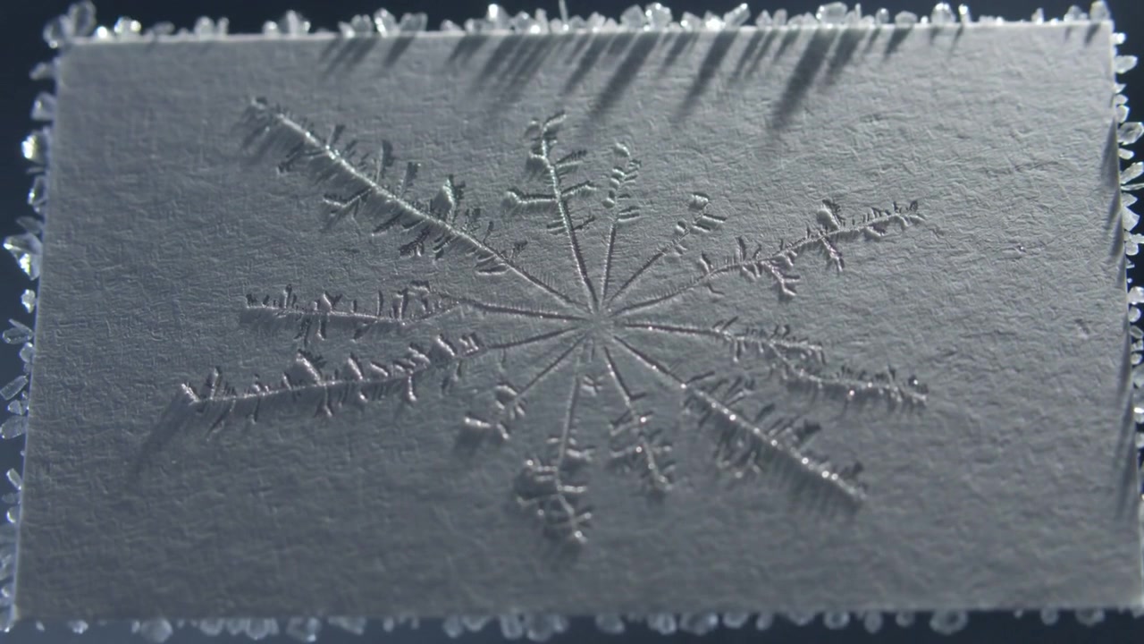 Growing crystals forming on textured white card, embossed star guiding edge growth under light