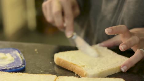 Junge-Frau,-Die-Damit-Beschäftigt-Ist,-Brot-Zu-Buttern,-Um-Sandwiches-Zum-Mittagessen-Zu-Grillen