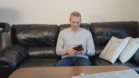 adult man on couch breaks down after discovering his wallet is empty