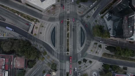 Vista-Aérea-De-Cerca-De-Una-Rotonda-Con-Coches,-Bicicletas,-Autobuses-Y-Gente-Caminando