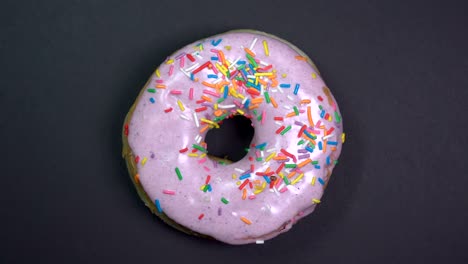 tasty and fresh sprinkled donut close-up macro shot spinning on a black background.