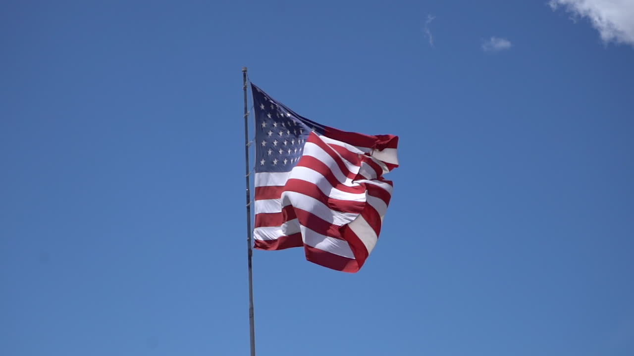 Amerikansk flag der vajer i vinden mod en blå himmel