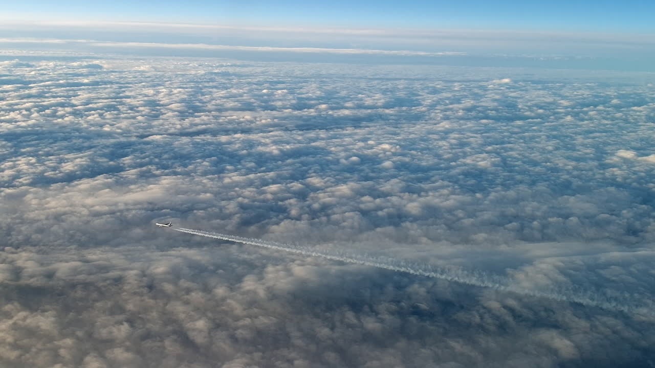 vista increíble desde la cabina de un avión que vuela alto por encima de las nubes dejando un largo rastro de aire de vapor de condensación blanco en el cielo azul