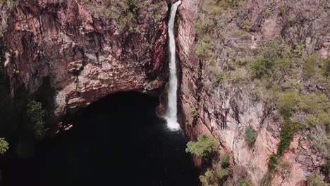 drone footage over tall waterfall flowing off cliff face into large canyon