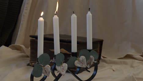 una mano enciende cuatro velas en el soporte para el ambiente ceremonial