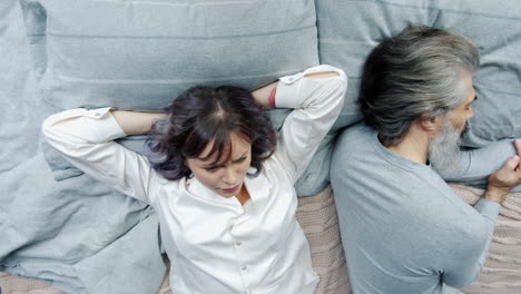 couple lying back to back in bed