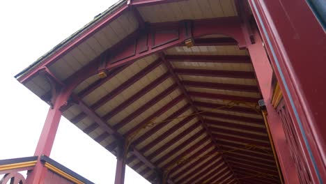 Ornate-Victorian-colourful-wooden-Swiss-bridge-grand-peaceful-public-park-gardens-low-angle-dolly-left-shot