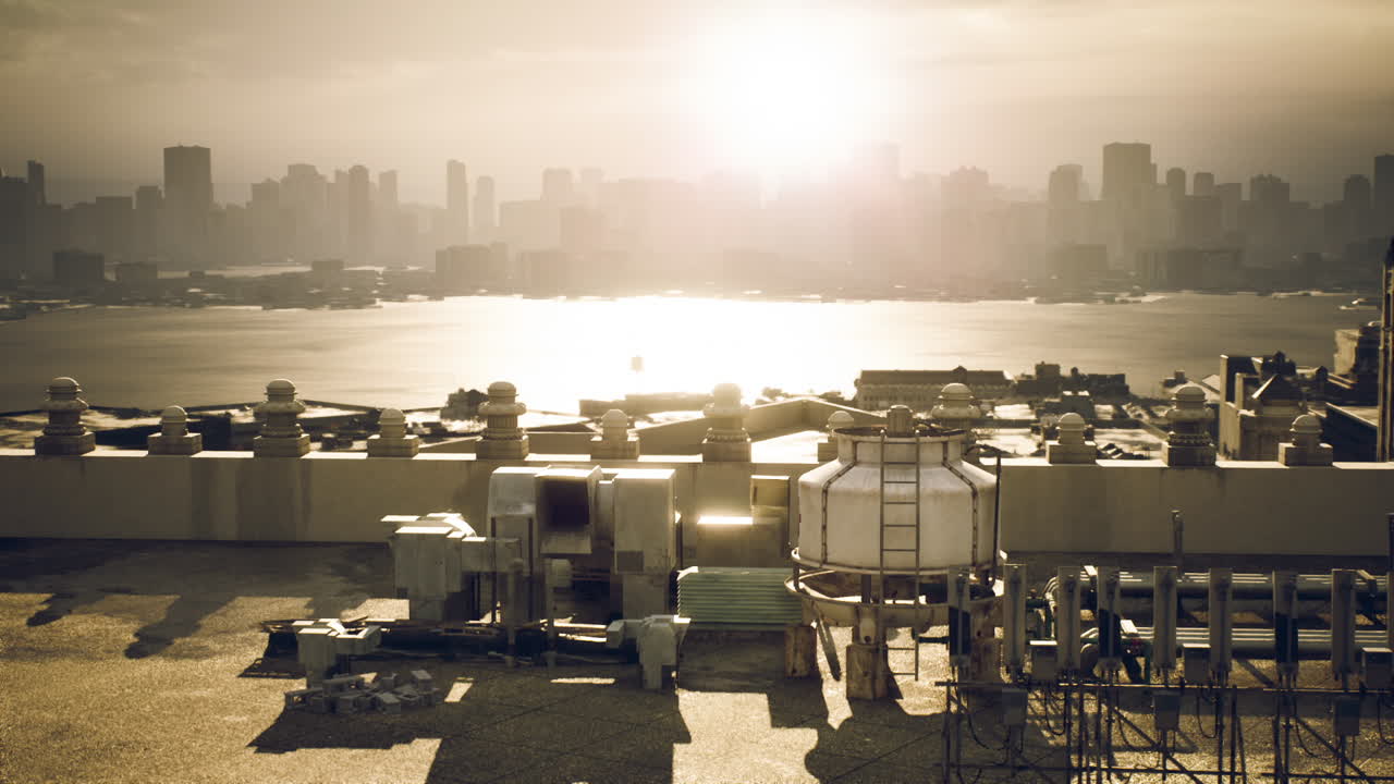 Sunset over a city skyline with industrial rooftops and tranquil waters