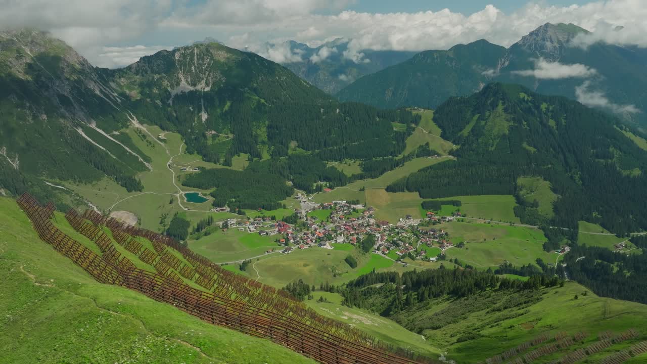 Ski village of Berwang Austria nestled in lush green mountains with snow breakers in the foreground